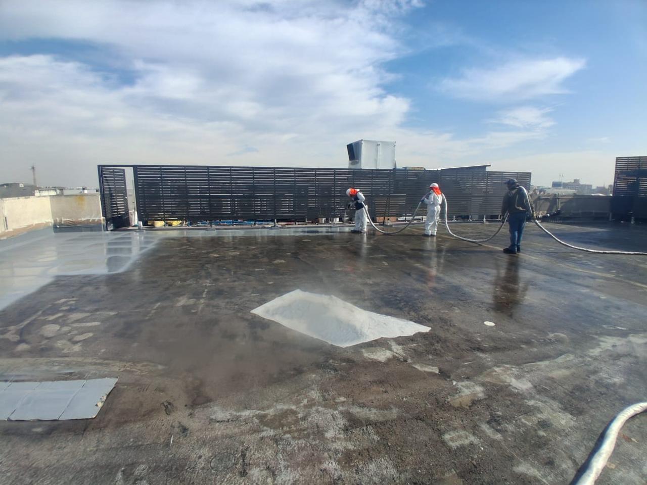 Equipo de Aispoltec aplicando membrana sobre la cubierta deteriorada de un edificio
