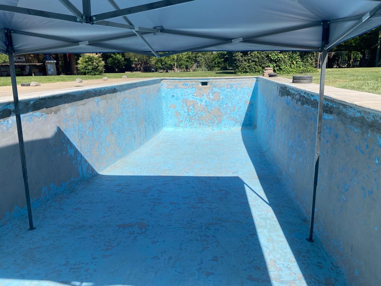 Piscina con pintura azul descascarada y superficie deteriorada antes del trabajo