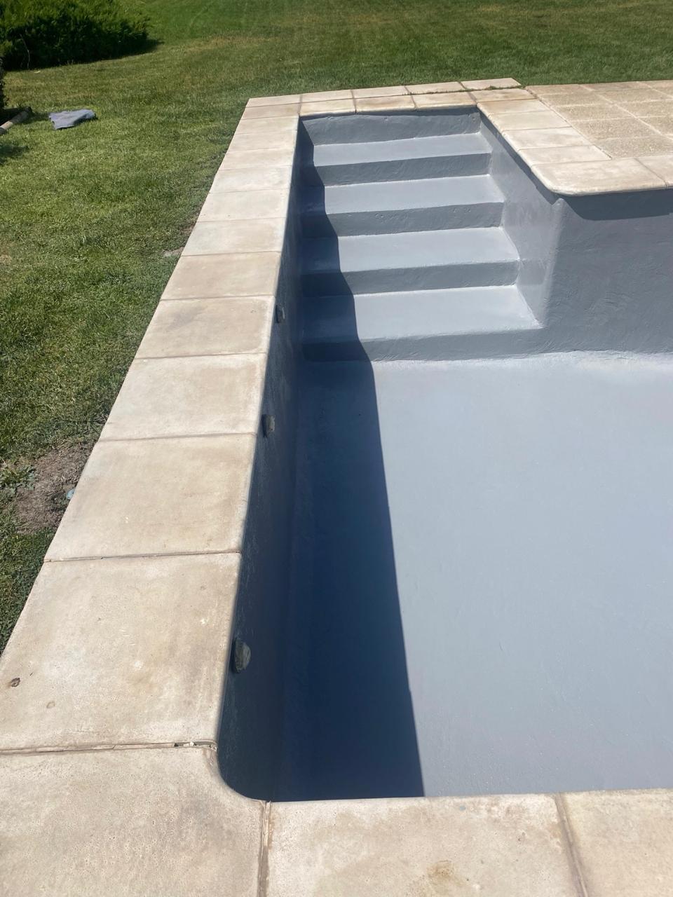 La misma piscina terminada con revestimiento gris uniforme y escalones sellados