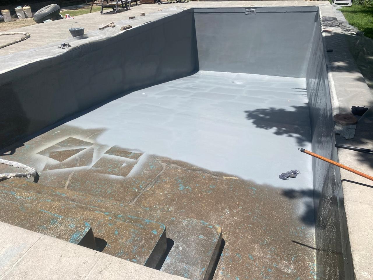 La misma piscina renovada con revestimiento continuo gris recién aplicado