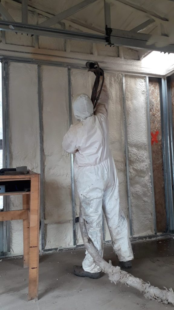 Operario de Aispoltec proyectando poliuretano expansivo entre pies derechos de tabiquería